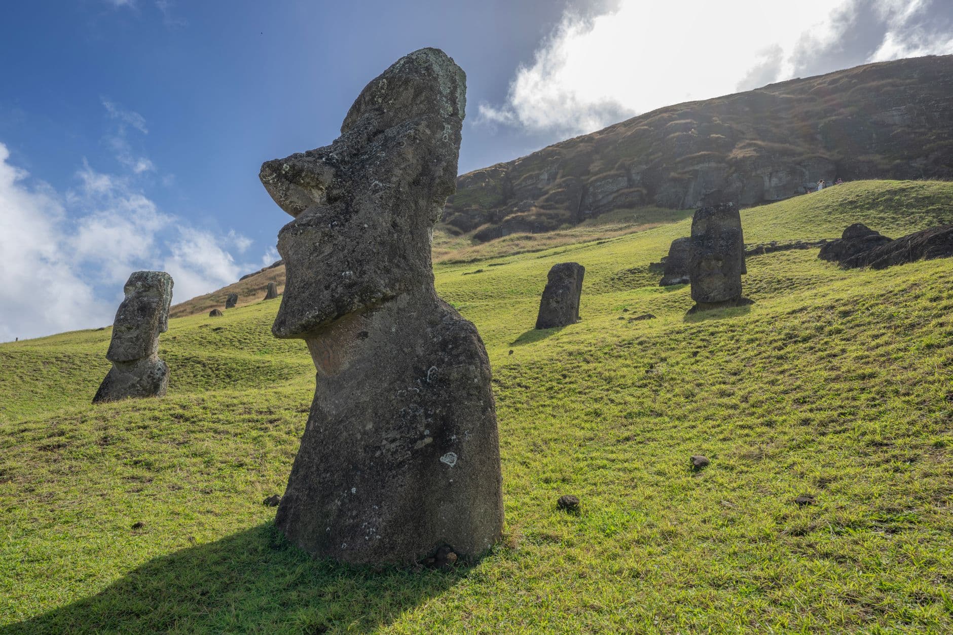 Iconic Moai statues standing on green hills under a bright sky on Easter Island.