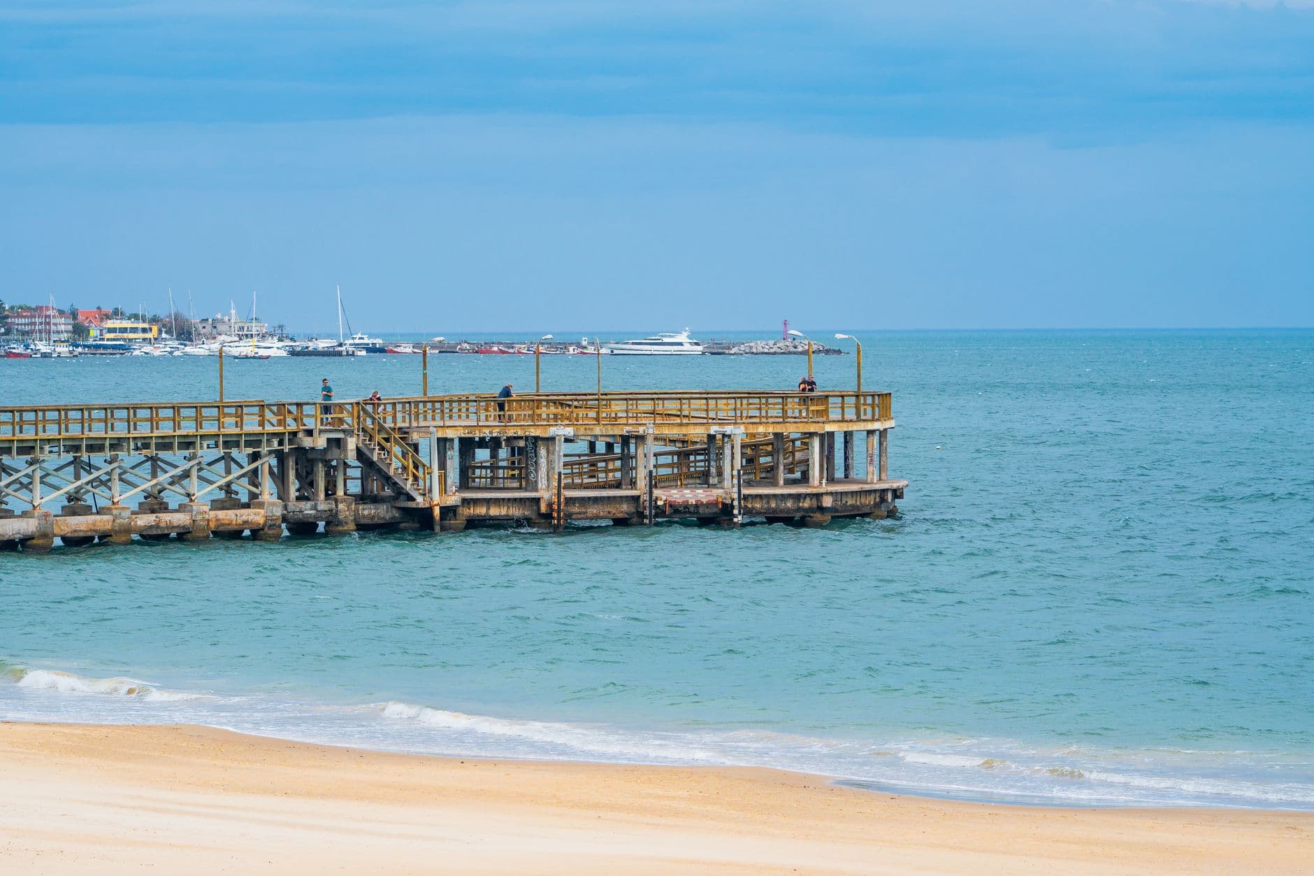 Tranquil view of a wooden pier and beach in Punta del Este, Uruguay on a sunny day.