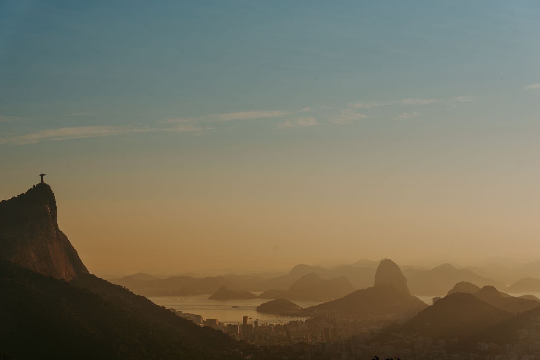 Breathtaking sunset view of Rio de Janeiro with the Christ the Redeemer statue and iconic Sugarloaf Mountain.