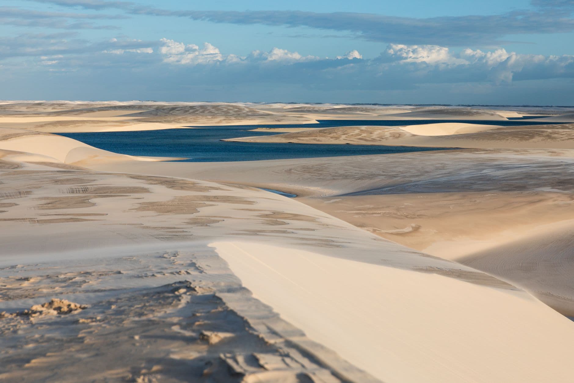 Breathtaking view of sand dunes and lagoons in Lençóis Maranhenses, Brazil, under a clear blue sky.
