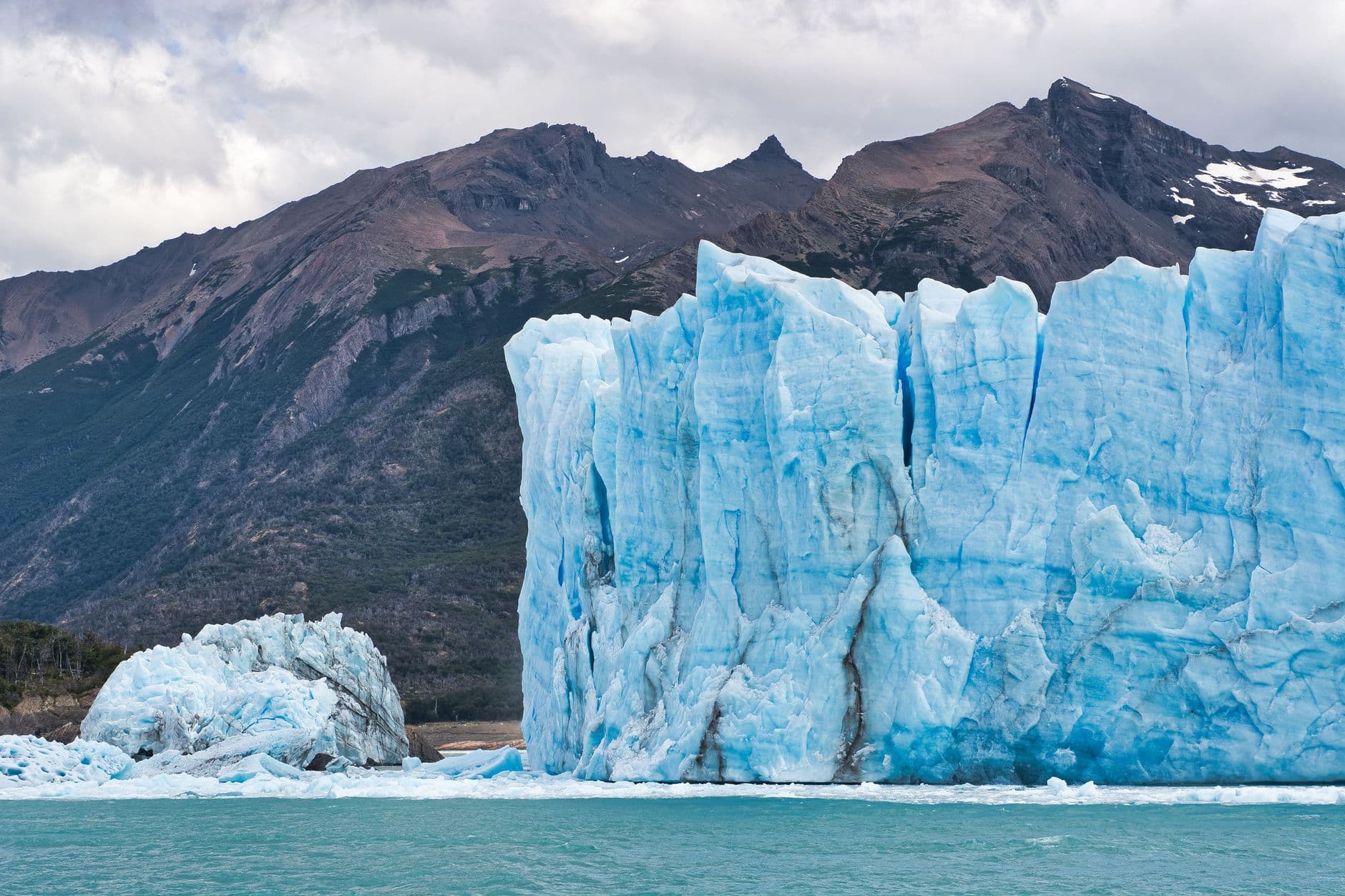 Breathtaking landscape of solid glacier on background of rocky mountains in winter on cloudy day