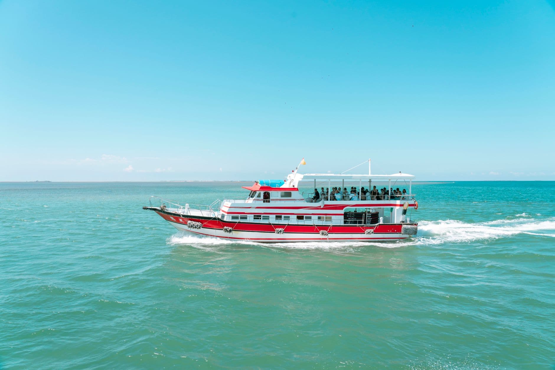 Vibrant red and white ferry sailing under sunny blue skies, providing a scenic water transportation experience.