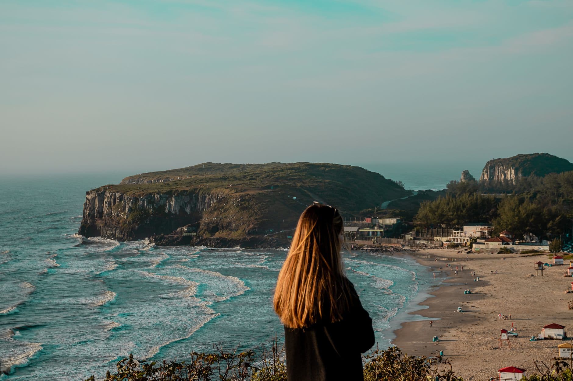 Woman gazing at the coastal cliffs and beach in Torres, Brazil, during daytime.