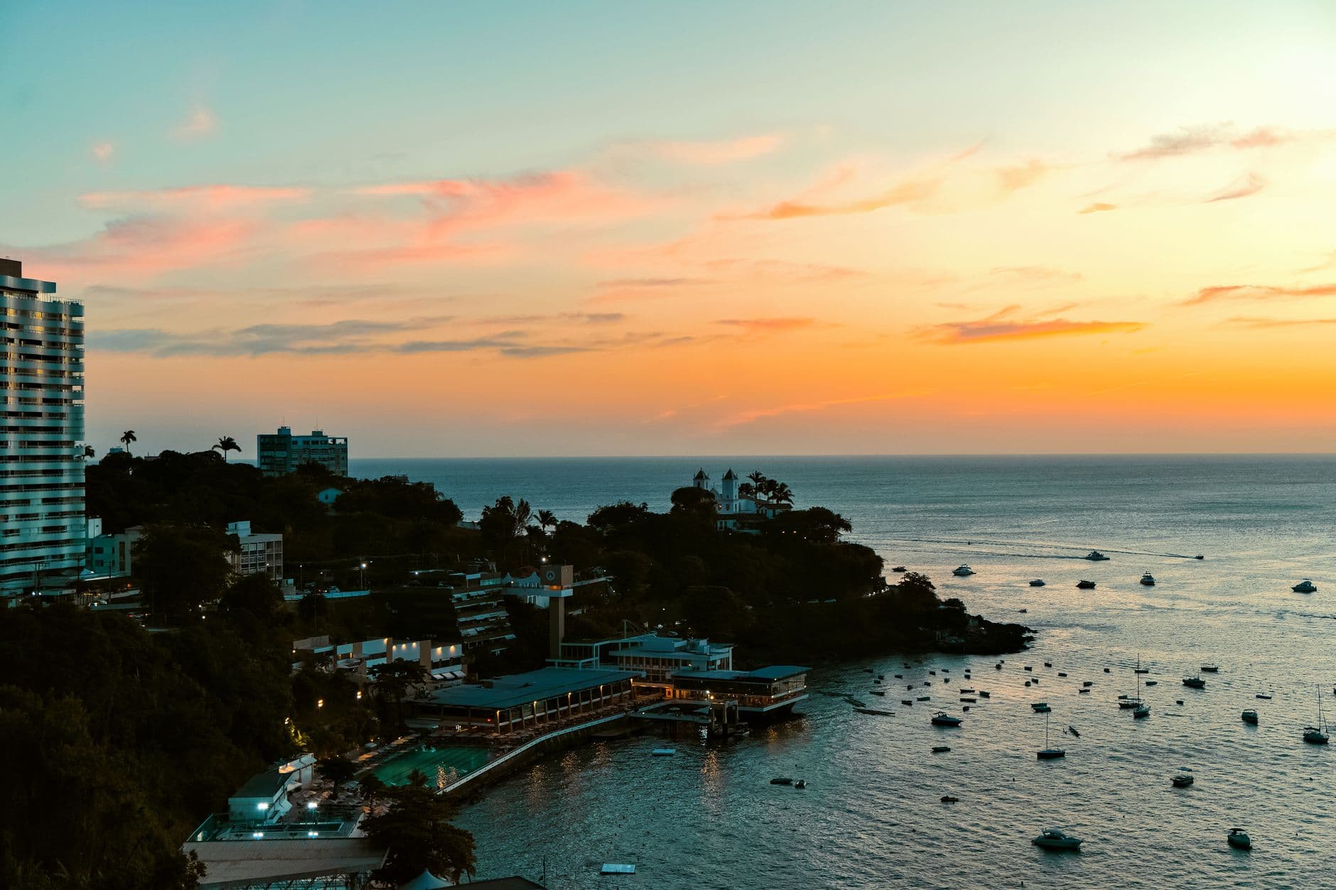Stunning aerial view of Salvador, Brazil's coastline at sunset with boats and cityscape.