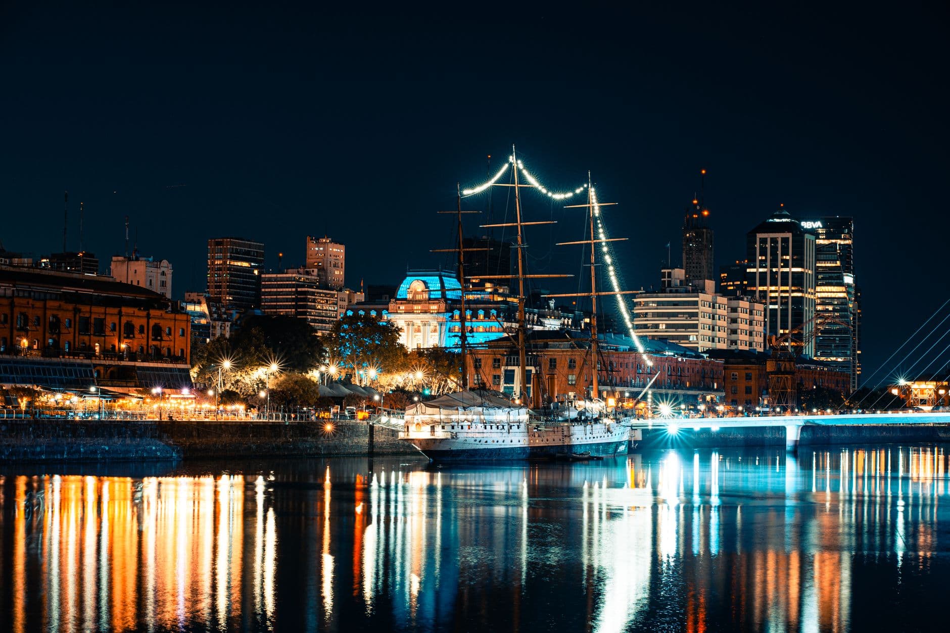 Illuminated Buenos Aires harbor at night with skyline reflections on the water.