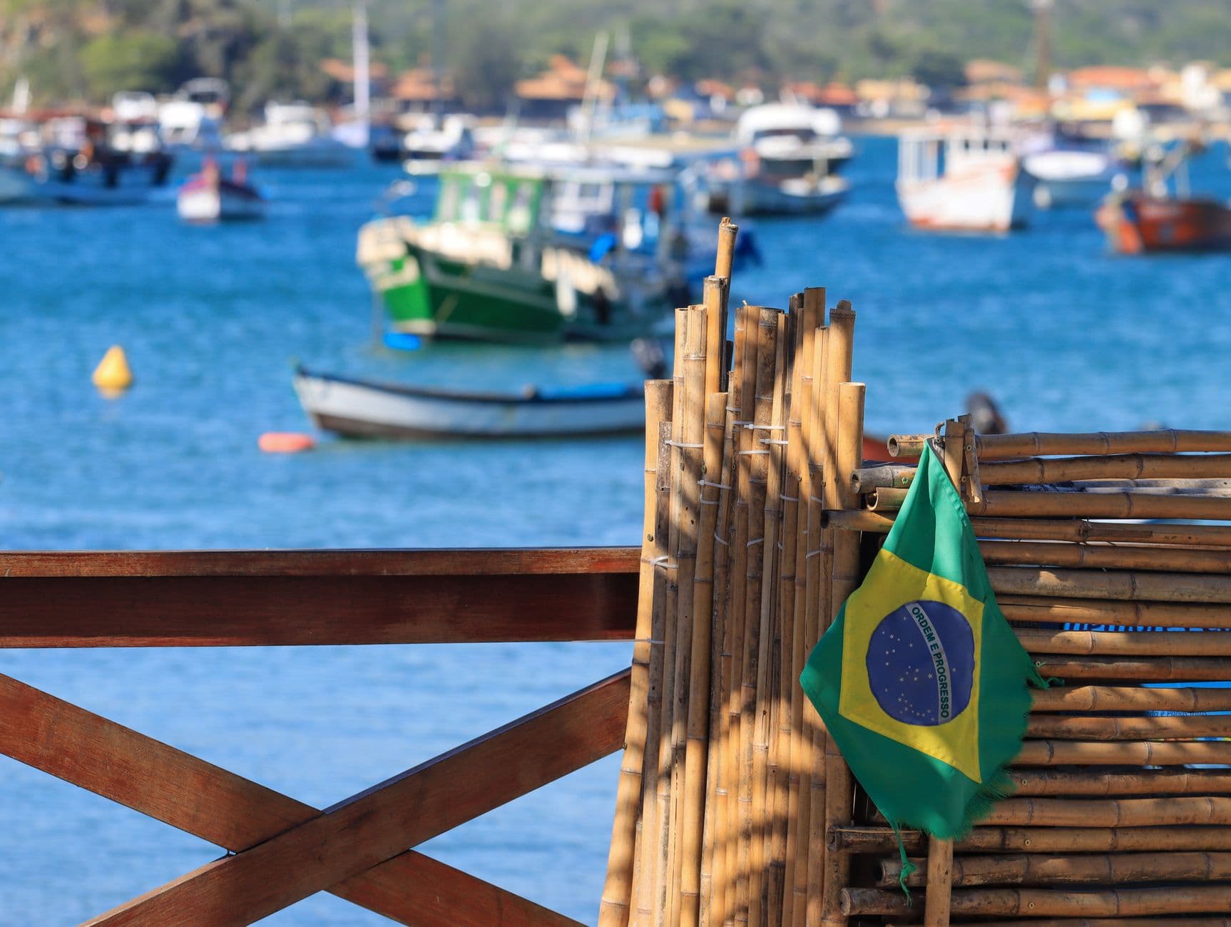 View of a Brazilian flag with boats in a bay, capturing coastal charm and nautical themes.