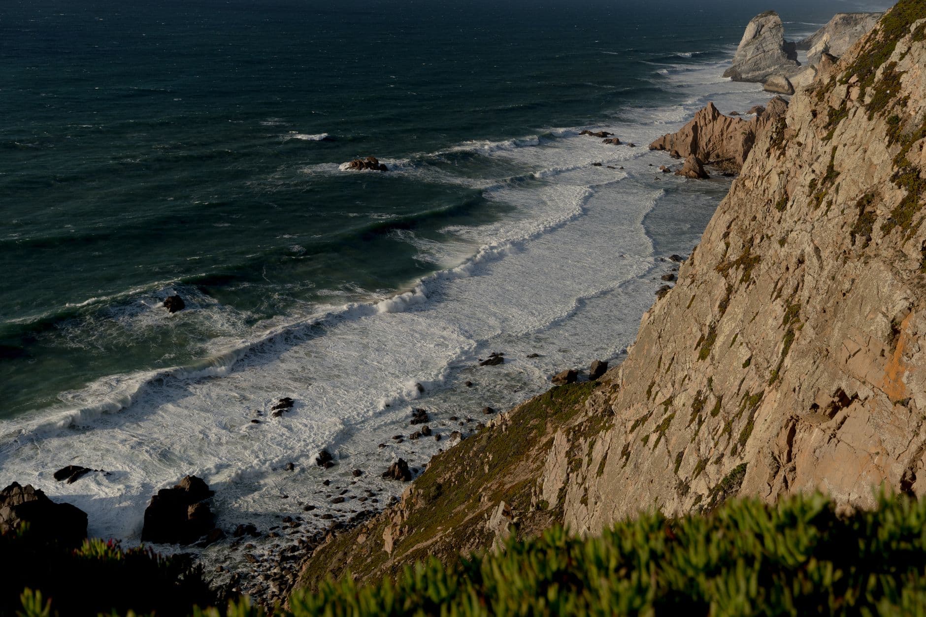 A stunning view of dramatic waves crashing against rocky cliffs under a clear sky.