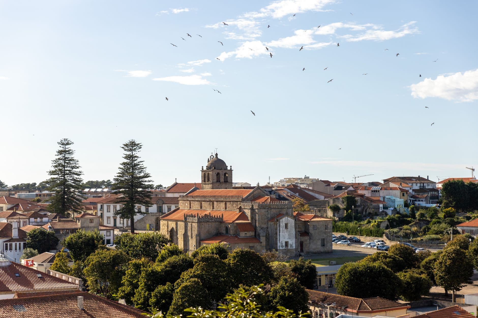 Scenic view of a historic church in Vila do Conde, Portugal with blue sky and green trees.
