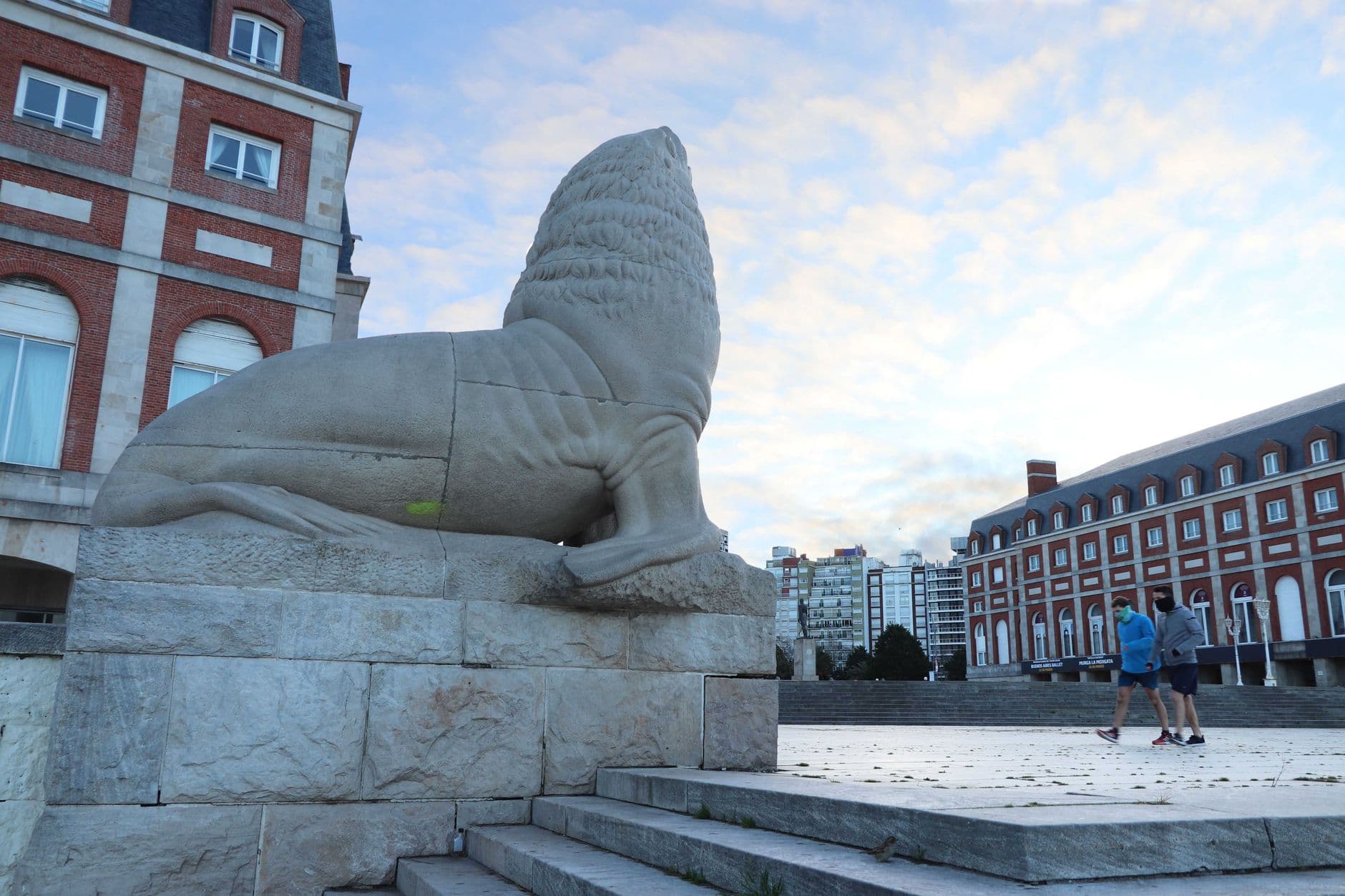 Stone sea wolf monument in Mar del Plata with iconic architecture in the background.