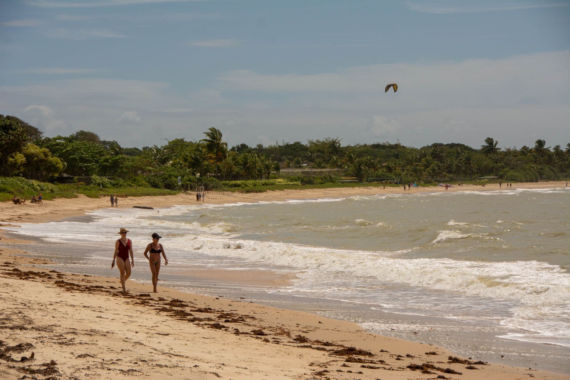 Two women walking on a sunny beach in Porto Seguro, Brazil, vibrant tropical scenery.