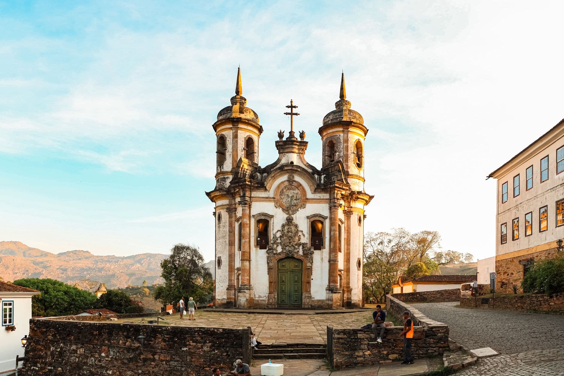 Beautiful baroque architecture of a church in Ouro Preto, Brazil, during daylight with people nearby.