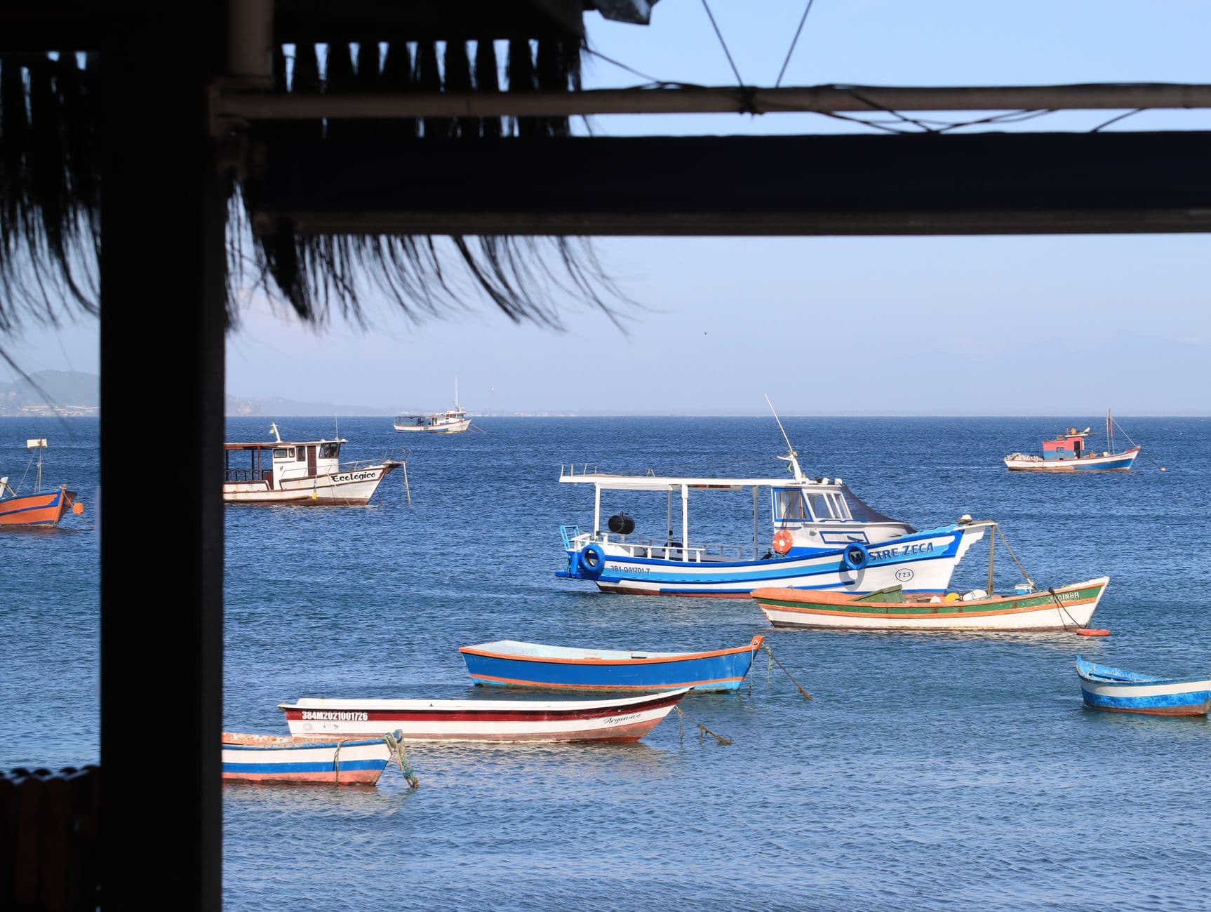 Peaceful seascape featuring traditional boats anchored in a serene coastal setting under a clear blue sky.