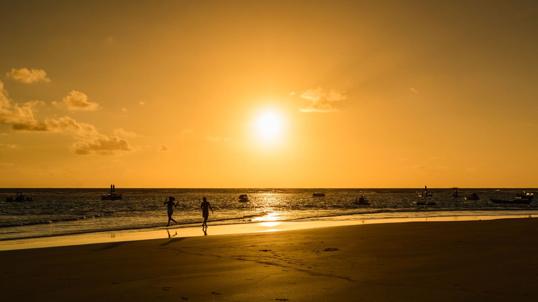 Golden hour at Porto de Galinhas with silhouettes against a vibrant sunset.